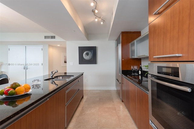 kitchen featuring light tile patterned flooring, sink, stainless steel oven, dark stone countertops, and black electric cooktop