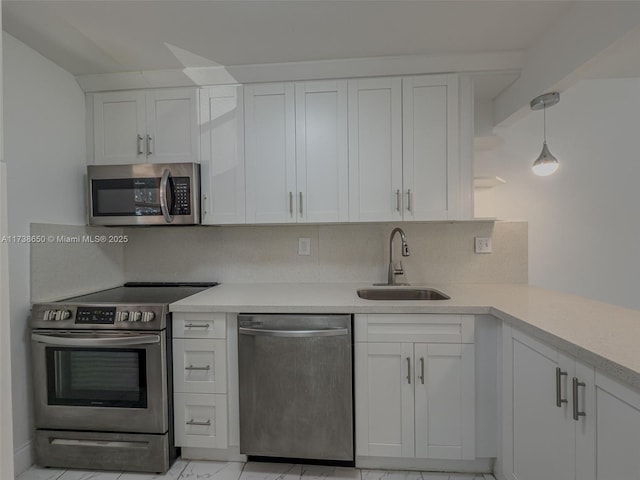 kitchen featuring sink, white cabinetry, pendant lighting, stainless steel appliances, and decorative backsplash