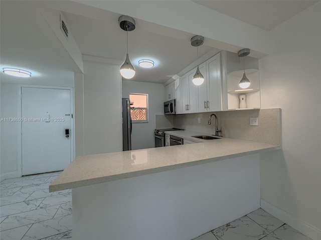 kitchen with appliances with stainless steel finishes, white cabinetry, sink, decorative backsplash, and kitchen peninsula