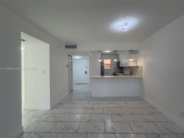 kitchen featuring white cabinetry, stainless steel fridge, kitchen peninsula, and sink