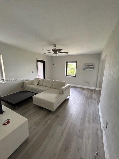 unfurnished living room with wood-type flooring, an AC wall unit, and ceiling fan