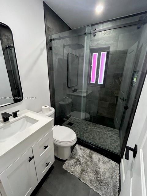 bathroom with vanity, a shower with door, and toilet