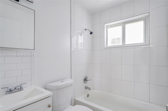 full bathroom featuring vanity, tiled shower / bath combo, and toilet