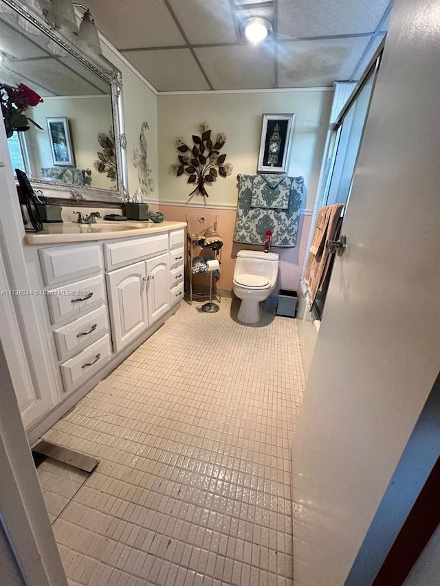 bathroom featuring a drop ceiling, vanity, a shower with shower door, and toilet