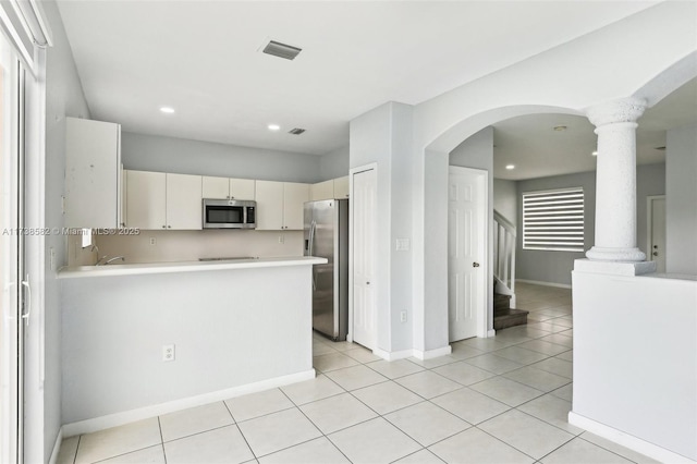 kitchen featuring light tile patterned floors, decorative columns, kitchen peninsula, and appliances with stainless steel finishes