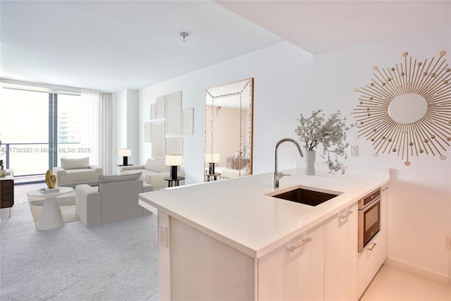 kitchen featuring sink, stainless steel oven, kitchen peninsula, light colored carpet, and a baseboard heating unit