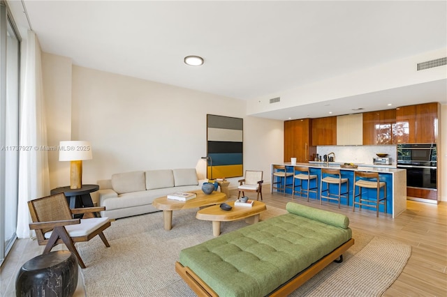 living room featuring sink and light hardwood / wood-style floors