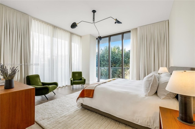 bedroom with a wall of windows and light wood-type flooring