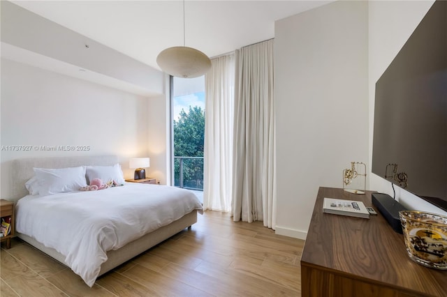 bedroom with light hardwood / wood-style floors and expansive windows