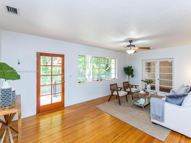 living room featuring french doors, ceiling fan, and light wood-type flooring