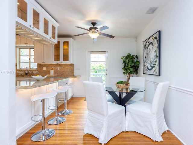 dining area with ceiling fan, sink, a wealth of natural light, and light wood-type flooring