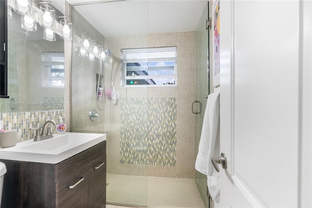 bathroom featuring vanity, a shower with shower door, tile walls, and decorative backsplash