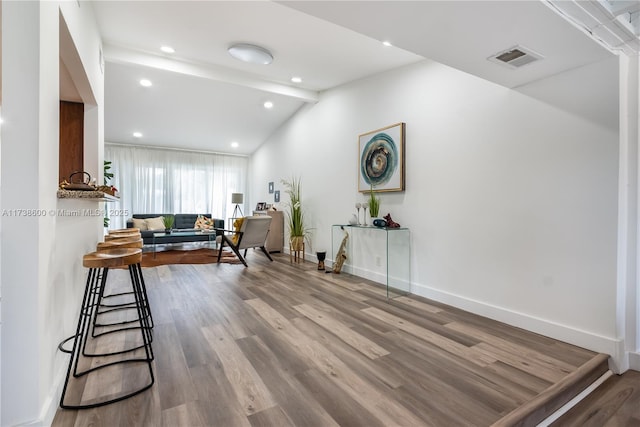 living room featuring vaulted ceiling with beams and light hardwood / wood-style flooring