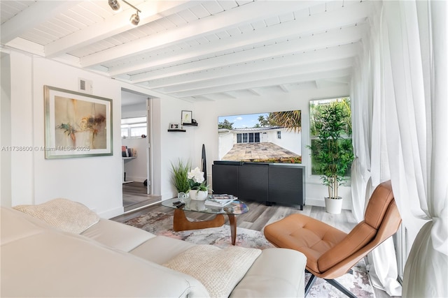 living room with beam ceiling, hardwood / wood-style flooring, and plenty of natural light