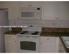 kitchen featuring white cabinetry, sink, and white appliances