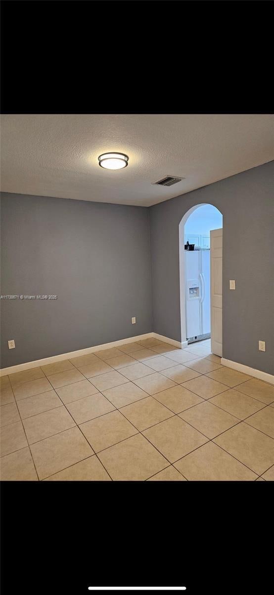 tiled spare room featuring a textured ceiling