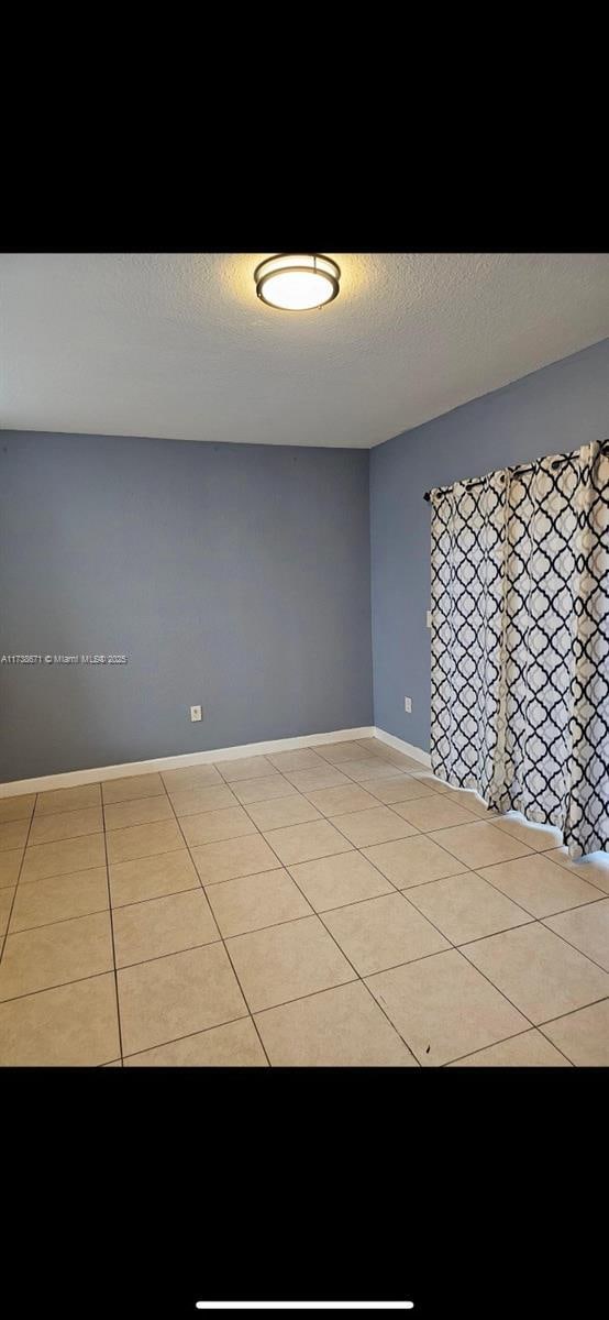 spare room with light tile patterned flooring and a textured ceiling