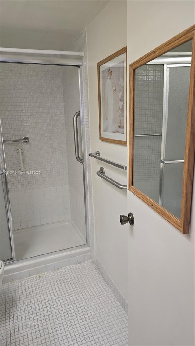 bathroom with toilet, a shower with shower door, and tile patterned flooring