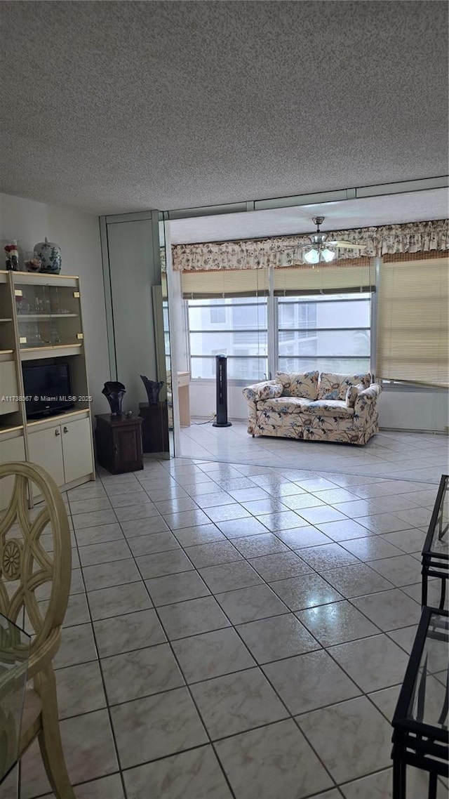 unfurnished living room with tile patterned flooring, ceiling fan, and a textured ceiling