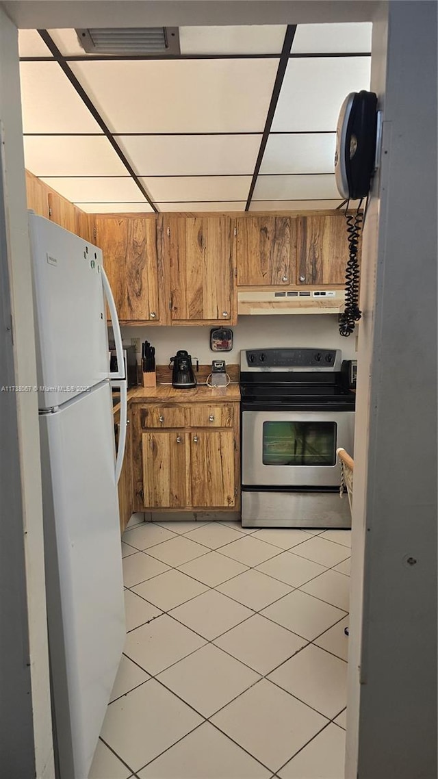 kitchen featuring light tile patterned floors, stainless steel electric stove, and white fridge