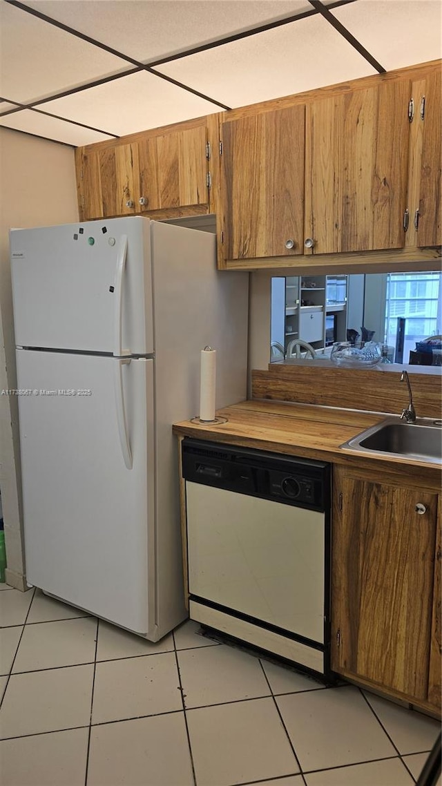 kitchen with white appliances, sink, and light tile patterned floors