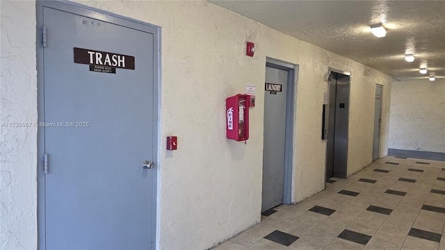 hallway with a textured ceiling and elevator