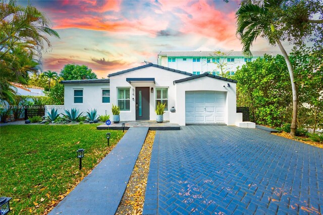 view of front of property featuring a garage and a lawn