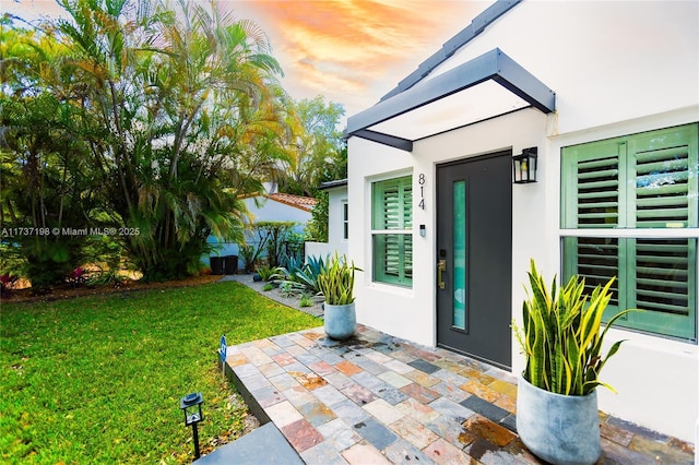 exterior entry at dusk with a yard and a patio area