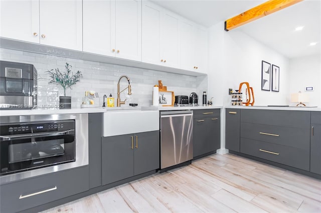 kitchen with sink, tasteful backsplash, stainless steel appliances, beam ceiling, and white cabinets