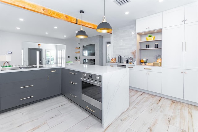 kitchen with white cabinetry, decorative light fixtures, light hardwood / wood-style flooring, black electric stovetop, and oven