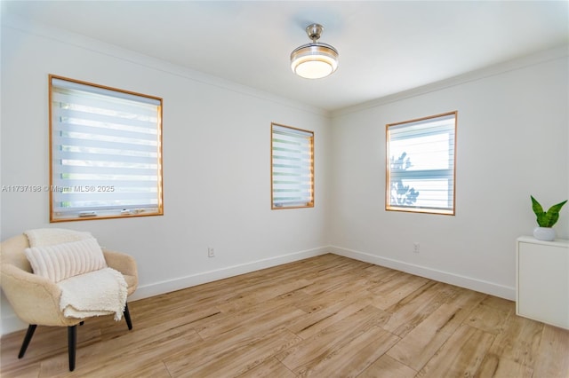 sitting room with ornamental molding and light wood-type flooring