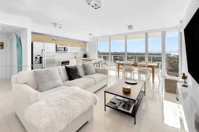 tiled living room with floor to ceiling windows, sink, and a textured ceiling