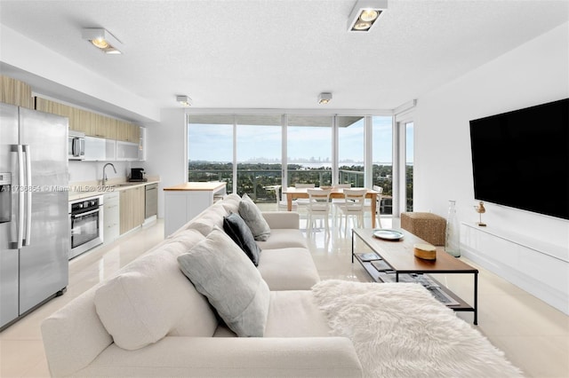 living room with sink, light tile patterned floors, expansive windows, and a textured ceiling