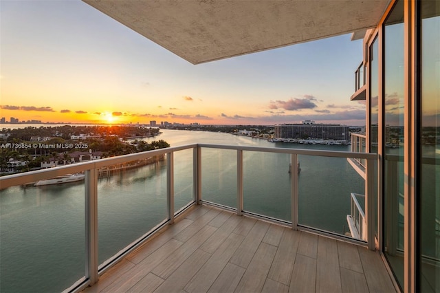 balcony at dusk featuring a water view