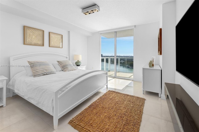 bedroom featuring floor to ceiling windows, access to exterior, a textured ceiling, and light tile patterned floors