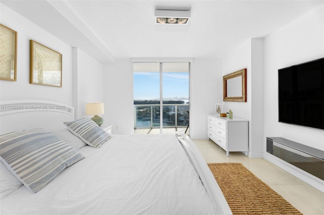 tiled bedroom with access to exterior, a wall of windows, and a textured ceiling