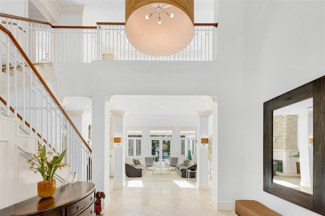 tiled foyer featuring ornate columns, crown molding, and a high ceiling