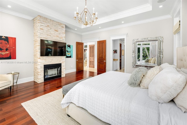 bedroom featuring dark hardwood / wood-style flooring, a fireplace, ornamental molding, and a raised ceiling