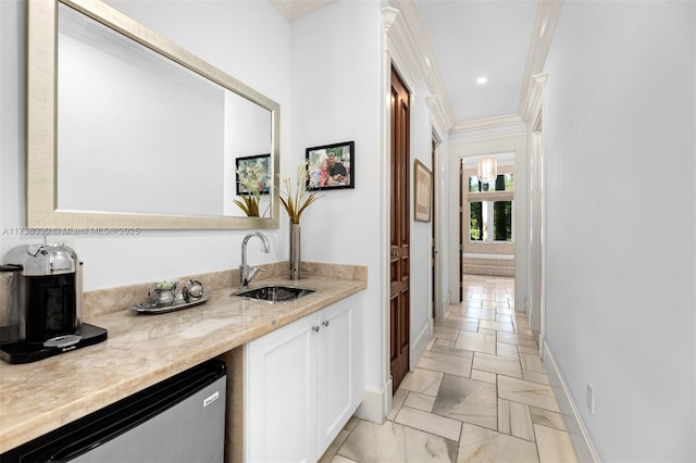 interior space featuring sink, stainless steel dishwasher, ornamental molding, light stone countertops, and white cabinets