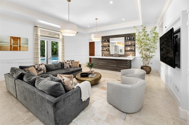 living room with a tray ceiling, ornamental molding, french doors, and bar area