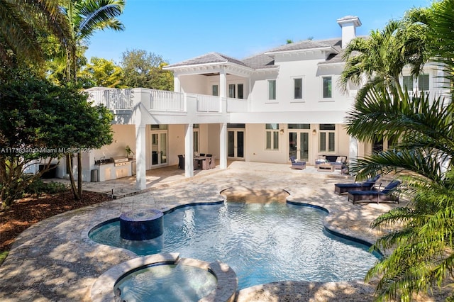 view of swimming pool with a patio, an outdoor kitchen, an in ground hot tub, and french doors