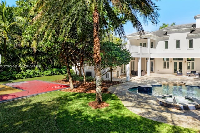 rear view of property with a patio, a balcony, a yard, and a pool with hot tub