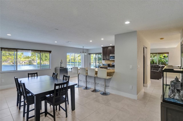 tiled dining space featuring a water view and a textured ceiling