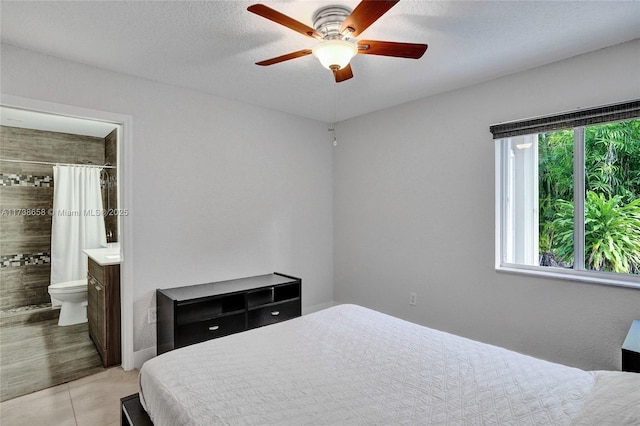 tiled bedroom with connected bathroom, a textured ceiling, and ceiling fan