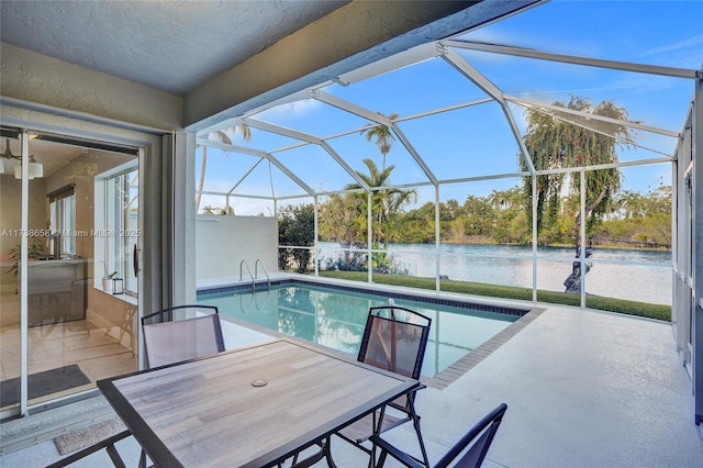 view of swimming pool featuring a water view, a patio area, and glass enclosure