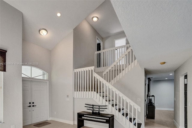 foyer entrance featuring a towering ceiling, a textured ceiling, and light tile patterned floors