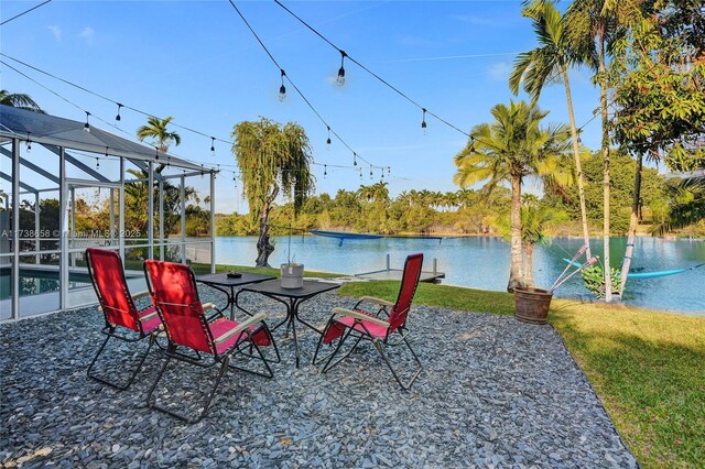 view of patio / terrace featuring a water view and glass enclosure