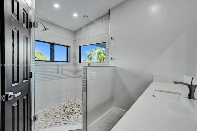 bathroom featuring a shower with door and vanity