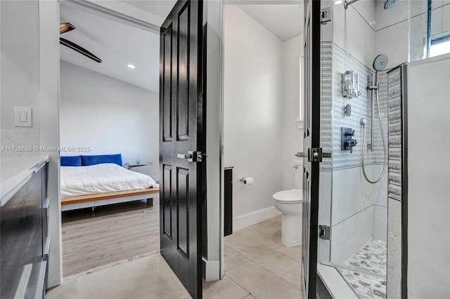 bathroom featuring a tile shower, tile patterned flooring, lofted ceiling, and toilet