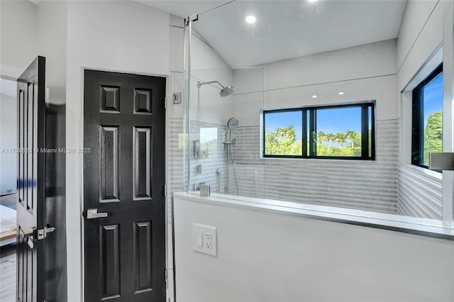 bathroom with a tile shower and lofted ceiling